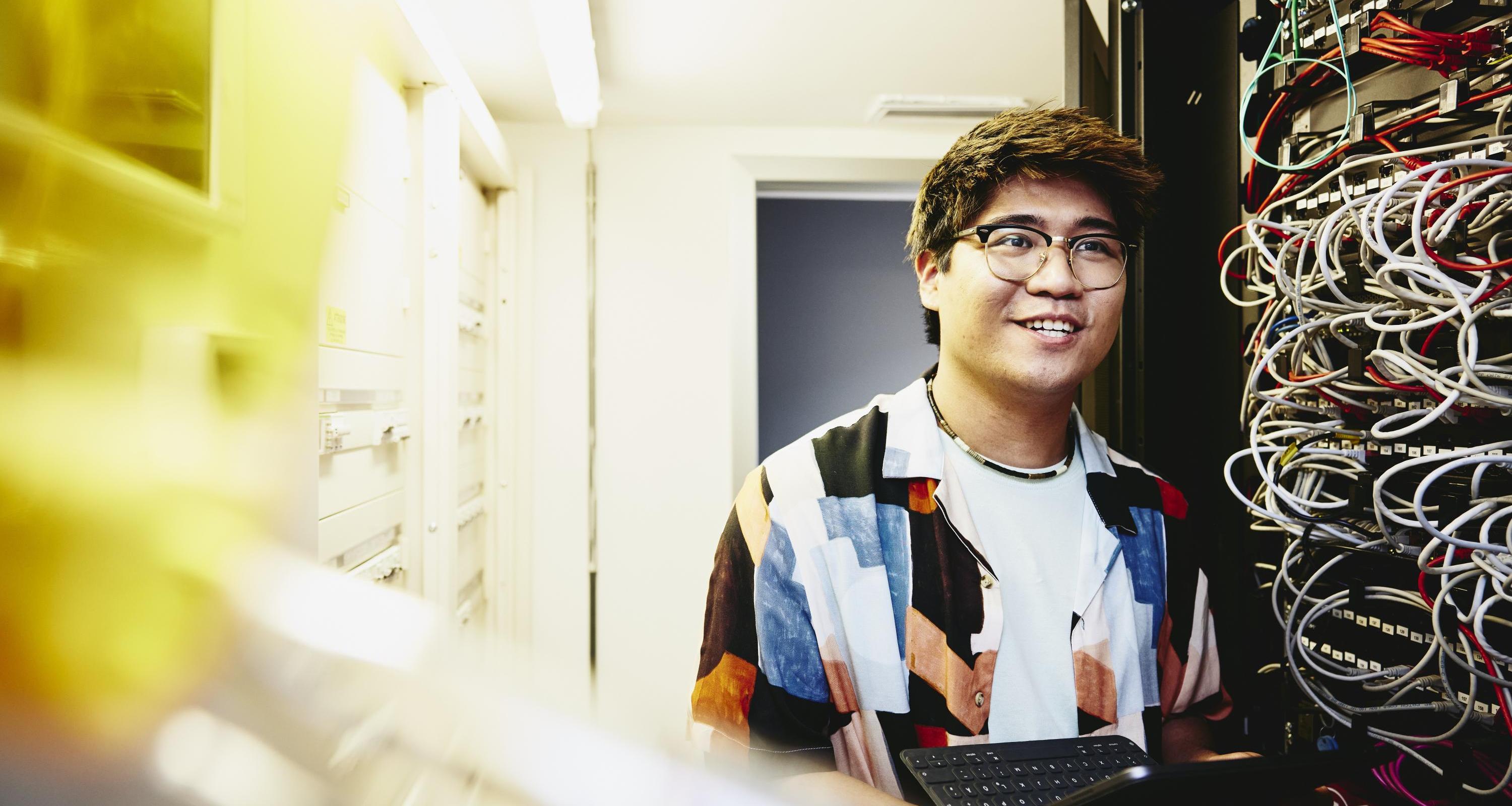 Smiling man holding an tablet standing in a servers room. Smiling man holding an tablet standing in a servers room.