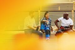 Two male and one female person sitting and chatting in a manufacturing environment