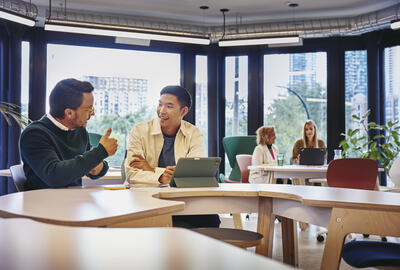 2 males having a discussion at a table with tablet in front of them 2 males having a discussion at a table with tablet in front of them