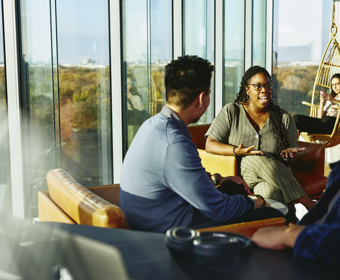 Two people having a conversation while sitting down in a lounge environment.
 Two people having a conversation while sitting down in a lounge environment.