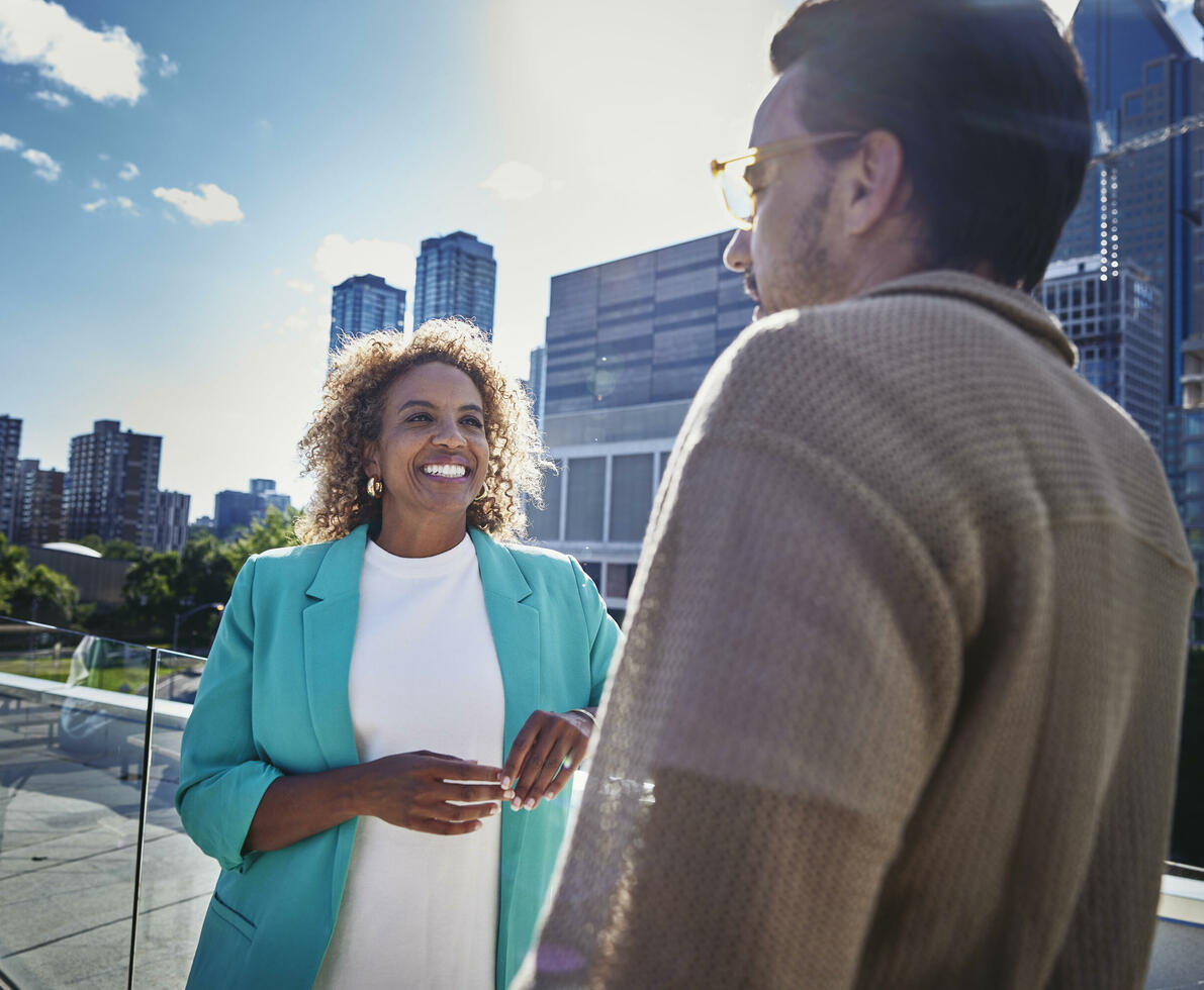 Female and male with glasses, standing outside on a balcony, talking Female and male with glasses, standing outside on a balcony, talking