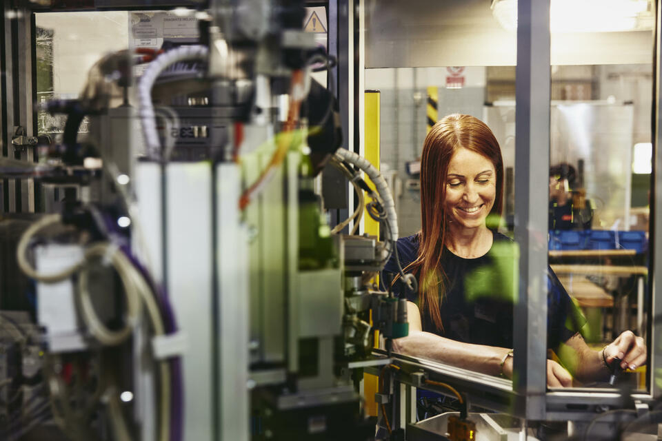 Smiling female operating a machine on a production site. 
 Smiling female operating a machine on a production site.