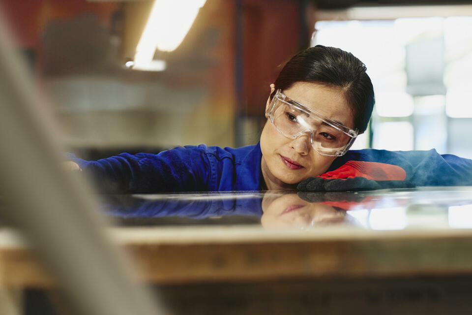 Womale wearing safety glasses and gloves watching a process closely.
 Womale wearing safety glasses and gloves watching a process closely.